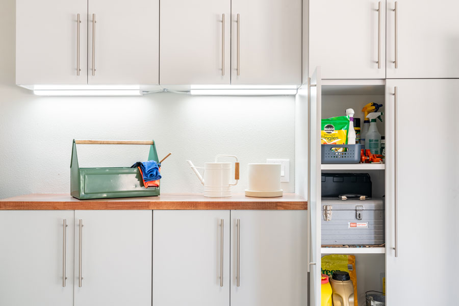 White cabinets in a garage with a few tools on a countertop